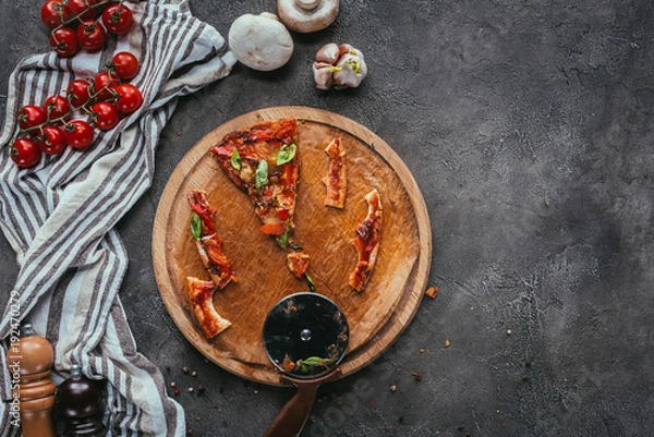 Fototapeta top view of pieces of eaten pizza with cutter on concrete table