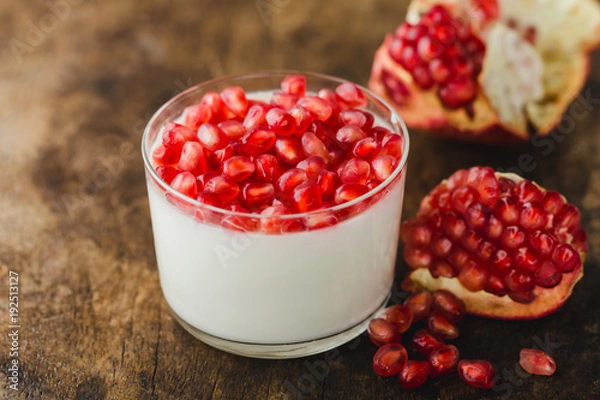 Obraz homemade yogurt with pomegranate seeds in jars on an old wooden table