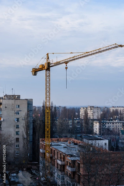 Fototapeta Tall construction crane at a building site