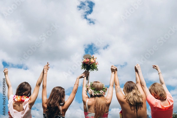 Obraz Girls raised their hands up on cloudy sky background at hawaii style hen party
