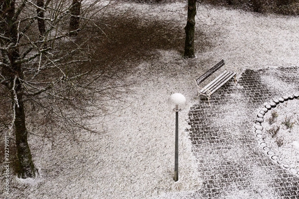 Fototapeta Park bench and slightly snow-covered ground from a bird's eye view