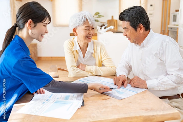 Obraz 笑顔で相談する高齢夫婦と介護スタッフ