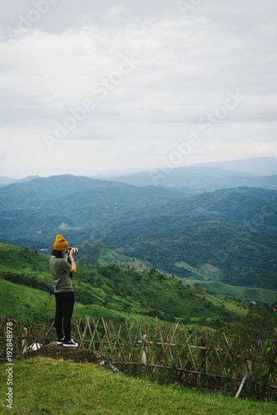 Fototapeta Woman talking picture of landscape on Doi Chang Moob viewpoint. This place locateed in Chiang Rai, Thailand.