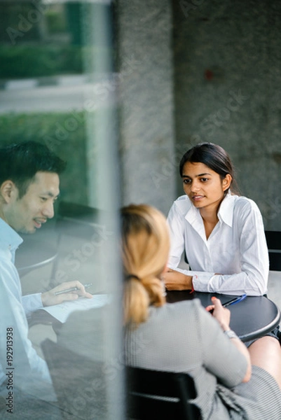 Fototapeta A young and attractive Asian Indian woman is interviewing for a job. She is smiling and is relaxed and calm