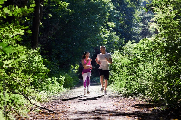 Obraz A man and a sportive woman Jogging in the woods in the morning.