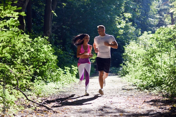 Obraz A man and a sportive woman Jogging in the woods and talking.