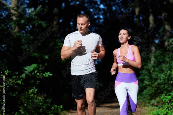 Obraz A man and a woman sporting on a Sunny day, do exercises in the forest.