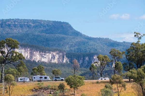 Fototapeta Car towing a caravan with mountains in the background
