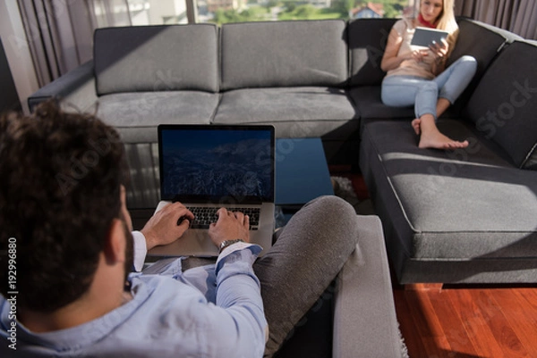 Fototapeta couple relaxing at  home using tablet and laptop computers