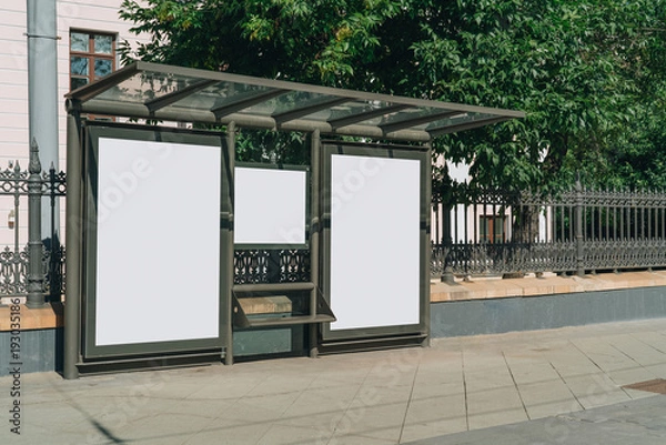 Obraz Dwa pionowe puste białe billboardy na przystanku autobusowym na ulicy miasta. W tle budynki i drzewa. Makieta. Plakat na ulicy obok jezdni. Słoneczny letni dzień.