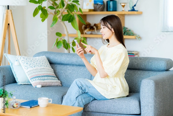 Obraz 部屋でスマホを操作する女性