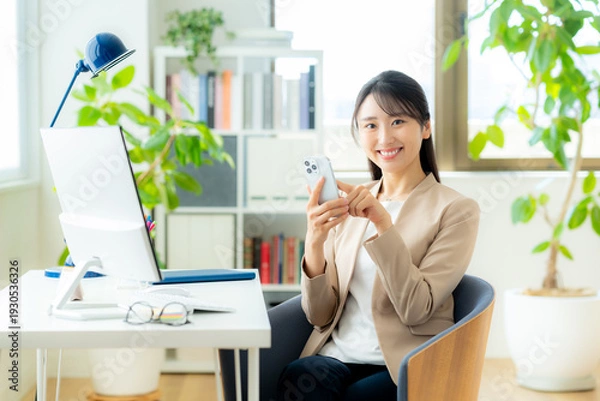 Obraz オフィスでスマホを使うビジネスウーマン