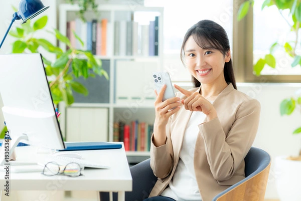 Obraz オフィスでスマホを使うビジネスウーマン