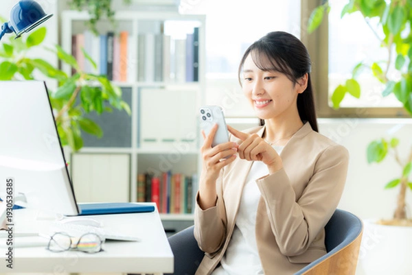 Obraz オフィスでスマホを使うビジネスウーマン