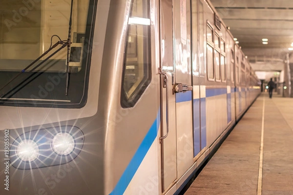 Fototapeta train subway underground with glowing lights luminous headlights and beams included from the front the whole length of the station platform tube