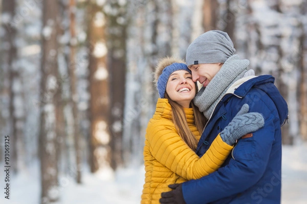 Fototapeta Portrait of happy young couple in a bright clothes in a winter forest