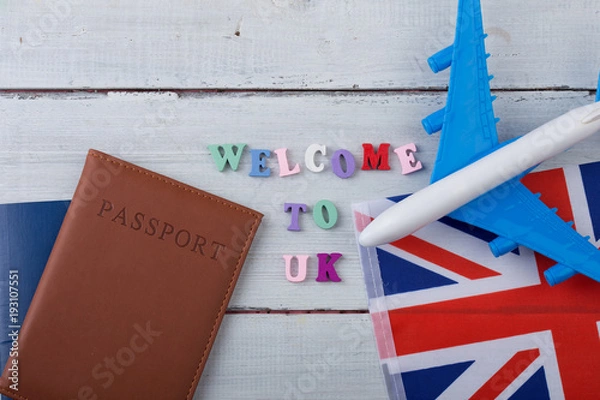 Fototapeta Travel time - colorful wooden letters with text "Welcome to UK" , flag of the United Kingdom, airplane model, passport