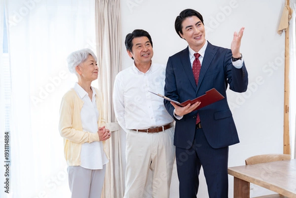 Obraz 高齢夫婦に説明するスーツ姿の営業マン｜介護・保険・住宅相談
