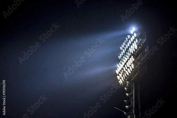 Fototapeta Light tower lit at a stadium during nightime.