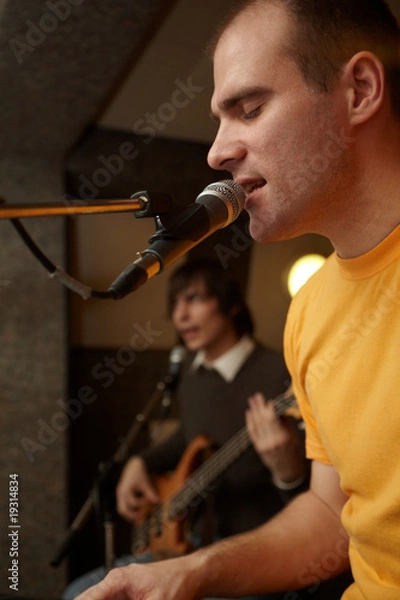 Fototapeta keyborder is playing and singing. guitar player in out of focus