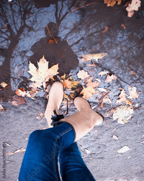 Fototapeta Girl wearing rain boots standing in a puddle on warm summer day