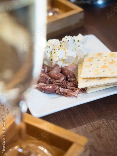 Obraz スパークリングワインとホタルイカ・クリームチーズ・クラッカーの盛り合わせ（前ボケ構図）