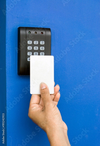 Obraz Door access control - young woman holding a key card to lock and unlock door., Keycard touch the security system to access the door