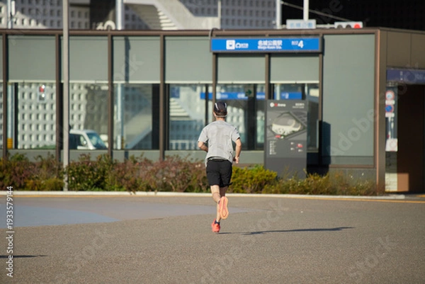 Obraz 春の名城公園でランニングする中年男性の姿