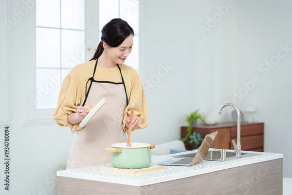 Obraz キッチンでパソコンを見ながら料理をする主婦