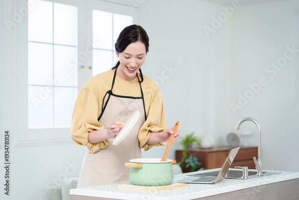 Obraz キッチンでパソコンを見ながら料理をする主婦