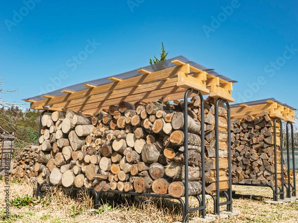 Obraz 冬を支える備え。青空の下で出番を待つ薪棚