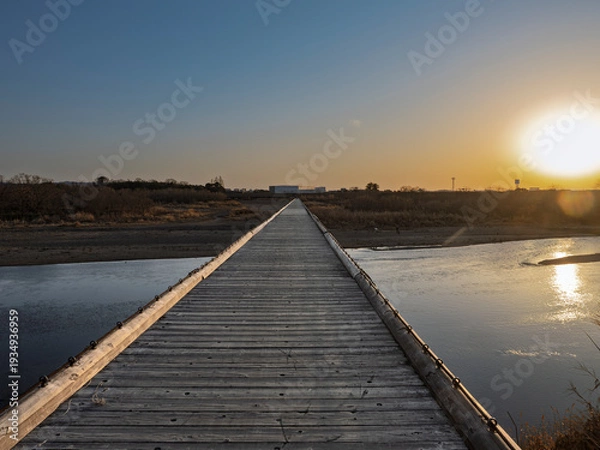Obraz 夕陽に消える道。黄金に輝く木造の流れ橋