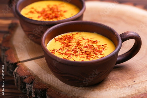 Fototapeta Indian turmeric milk with saffron, cardamom and turmeric. Copyspace