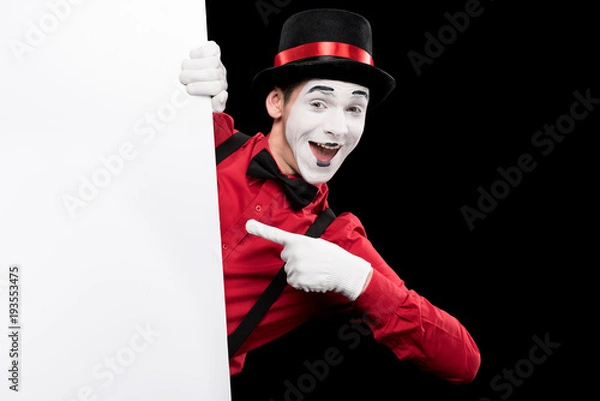 Fototapeta mime pointing on empty board isolated on black