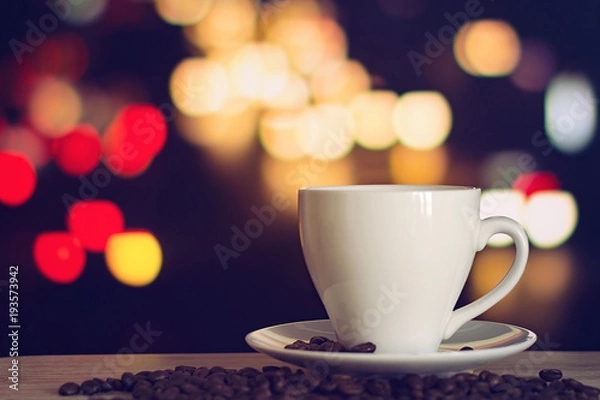 Fototapeta cup of coffee on wooden table with defocus bokeh of coffee shop background. Image with soft focus and blurred background.