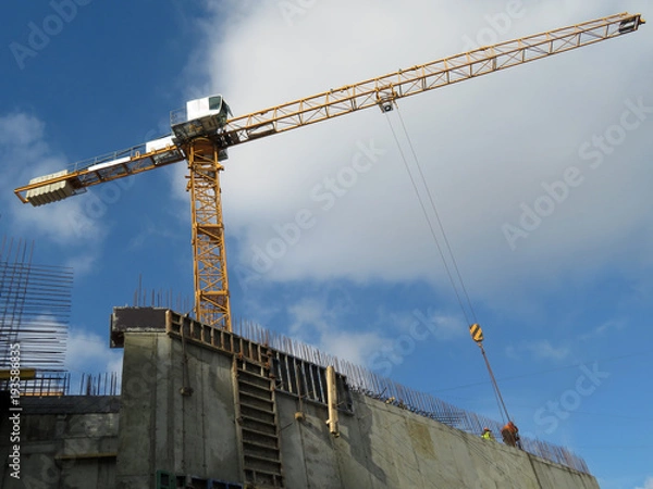 Fototapeta Crane on the construction site against the cloudy blue sky