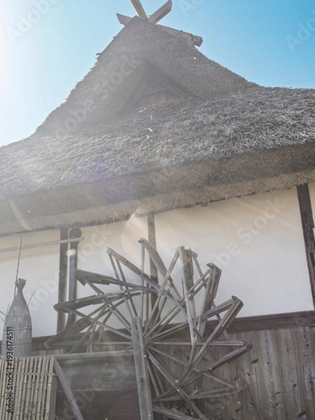 Obraz 陽光に包まれる茅葺屋根。水車が回る古き良き日本の原風景