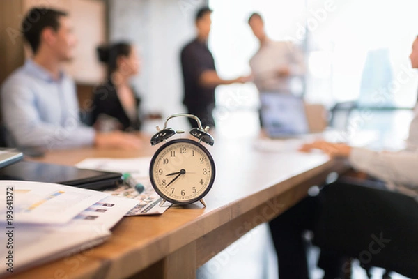 Fototapeta Vintage alarm clock in business office with blur business people working background.