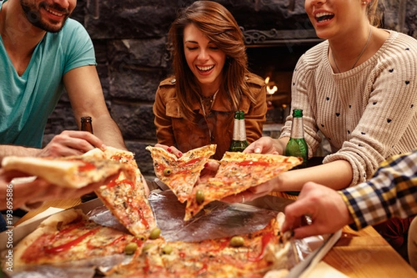 Obraz śmiejąc się przyjaciele jedzą pizzę i dobrze się bawią. Lubią razem jeść i pić