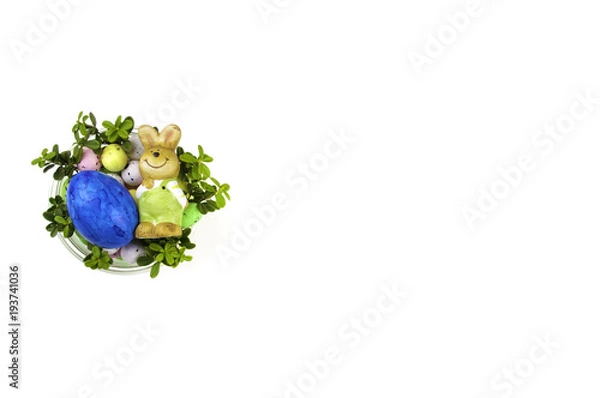 Fototapeta Funny little rabbit among Easter eggs in velour grass isolated on white
