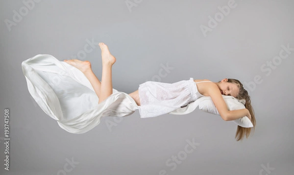 Fototapeta Sleeping girl. Flying in a dream. White linen flying through the air.