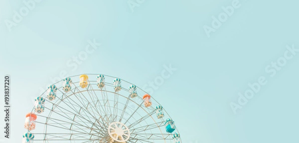 Fototapeta Retro colorful ferris wheel of the amusement park in the blue sky background.