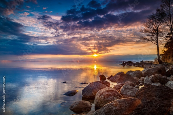 Fototapeta colorful sunset by a lake with a rocky beach