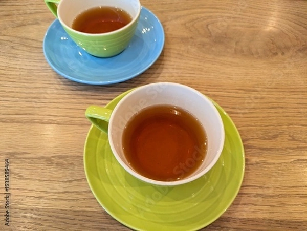 Obraz 色鮮やかなカップ＆ソーサーに入ったハーブティーと木目調のテーブルの風景