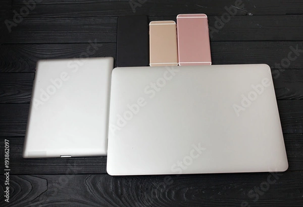 Fototapeta Minimalistic flat lay composition of black & white laptop computer keyboard, cell phone gadget on textured wooden desk table background in bright light. Workspace top view, copy space