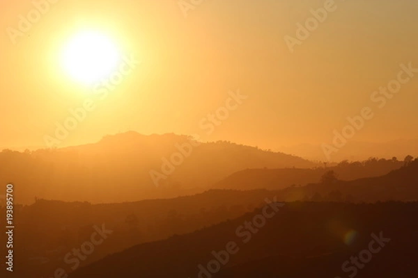 Obraz bright yellow sun by a silhouette of layers of mountains