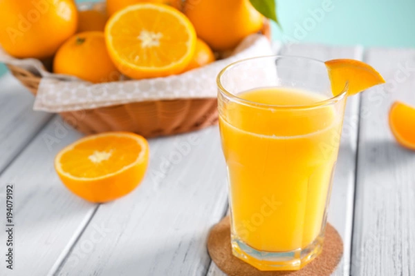Fototapeta Glass with fresh orange juice and fruit on wooden table