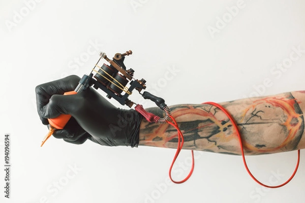 Fototapeta Man's Hand Holding Tattoo Machine na białym tle. czerwone przewody