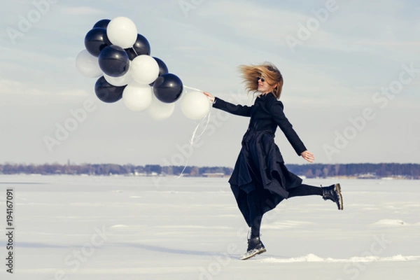 Obraz A woman with balloons is having fun in the winter on a snowy background