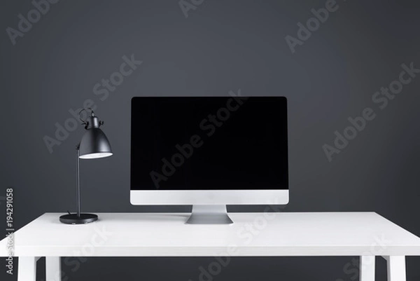 Obraz modern desktop computer with blank screen and lamp on table at workspace